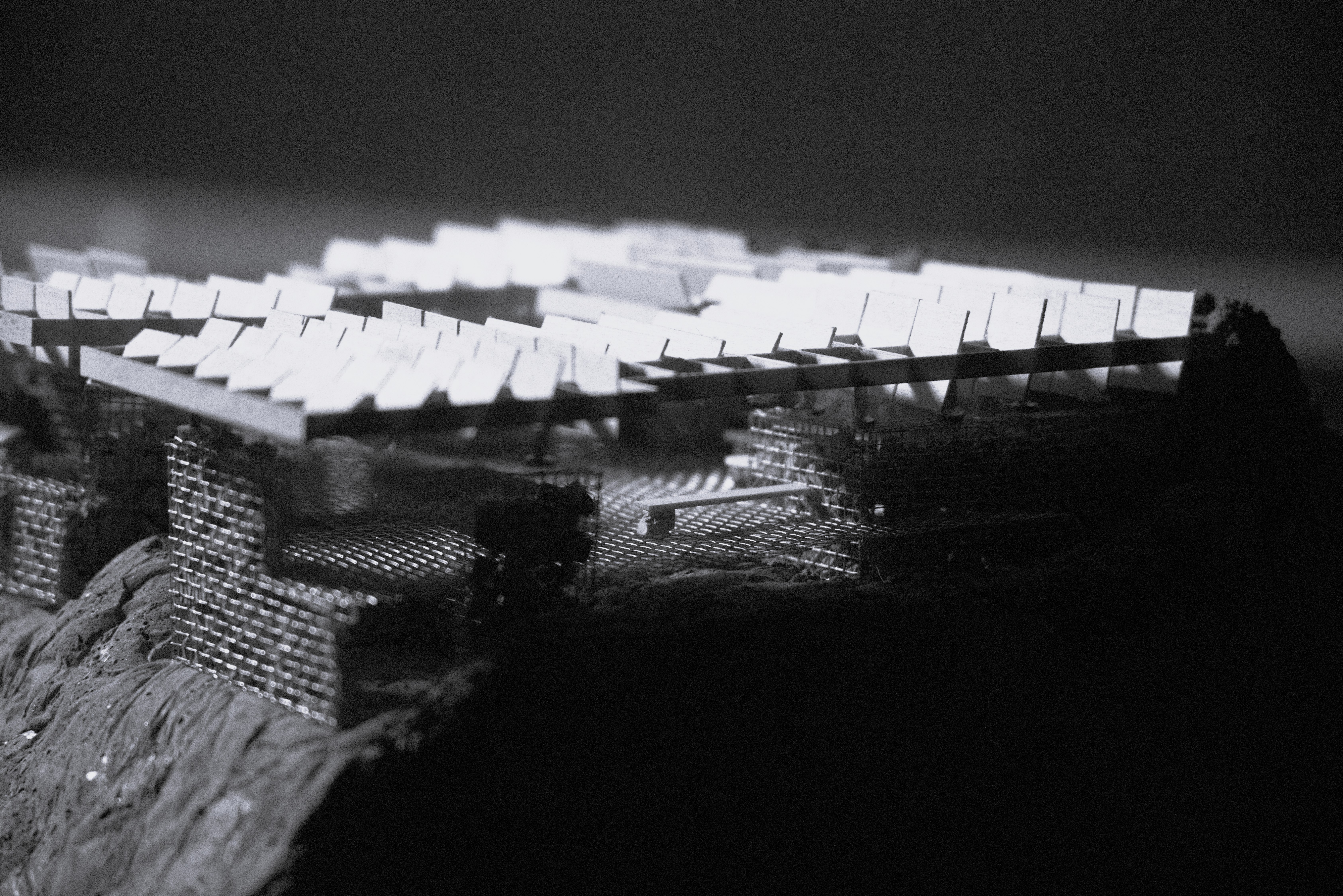 Black-and-white physical model of Curanto Cookhouse with mesh gabion walls and a slatted roof